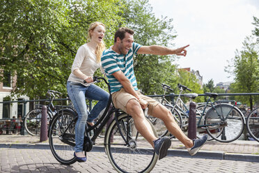 Niederlande, Amsterdam, glückliches Paar beim Fahrradfahren in der Stadt - FMKF002112