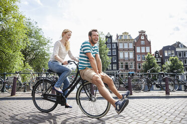 Netherlands, Amsterdam, happy couple riding bicycle in the city - FMKF002089