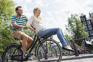 Niederlande, Amsterdam, glückliches Paar beim Fahrradfahren in der Stadt - FMKF002091