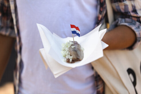 Woman holding napking with matjes herring and Dutch flag - FMKF002118
