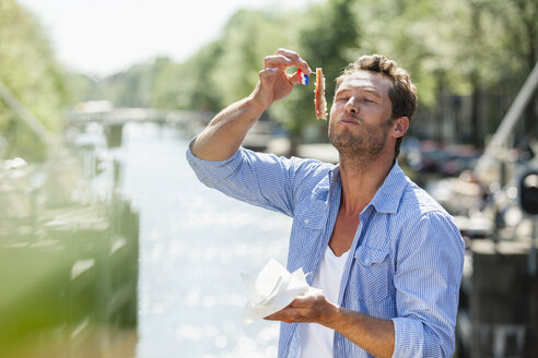 Netherlands, Amsterdam, man eating matjes herring - FMKF002121