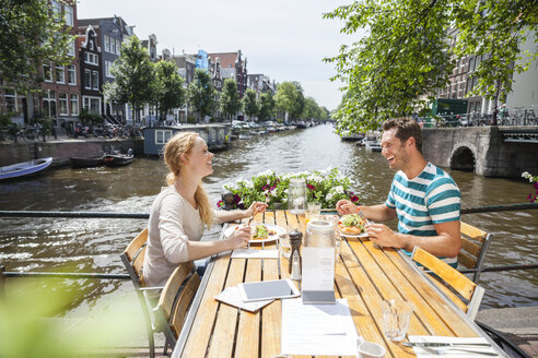 Niederlande, Amsterdam, glückliches Paar beim Mittagessen am Stadtkanal - FMKF002124