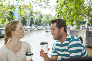 Niederlande, Amsterdam, Paar mit Kaffee zum Mitnehmen am Stadtkanal - FMKF002131