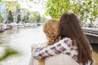 Niederlande, Amsterdam, zwei Frauen umarmen sich am Stadtkanal - FMKF002138