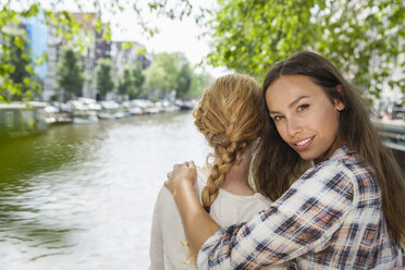 Niederlande, Amsterdam, zwei Frauen umarmen sich am Stadtkanal - FMKF002139