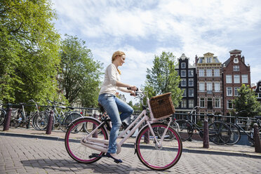 Niederlande, Amsterdam, Frau fährt Fahrrad in der Stadt - FMKF002145