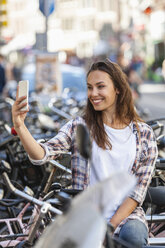 Netherlands, Amsterdam, smiling young woman taking a selfie - FMKF002158