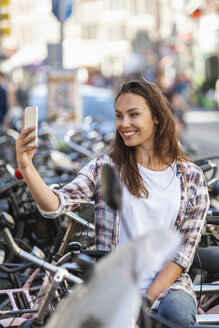 Niederlande, Amsterdam, lächelnde junge Frau, die ein Selfie macht - FMKF002158