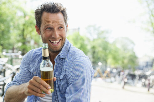 Niederlande, Amsterdam, glücklicher Mann trinkt Bier aus einer Flasche - FMKF002167