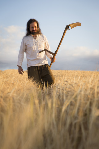 Organic farmer with scythe in barley field stock photo