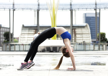 Sportliche junge Frau in Rad-Pose in der Stadt - PASF000012