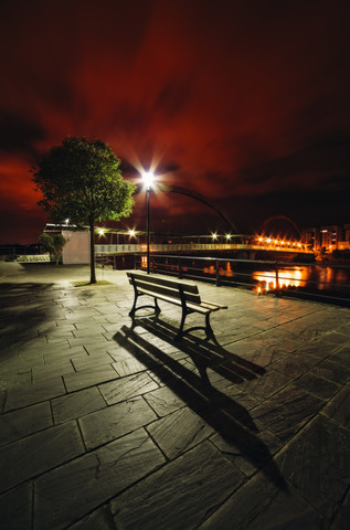 Spanien, Galicien, Naron, Promenade mit einer Bank im Vordergrund bei Nacht, lizenzfreies Stockfoto