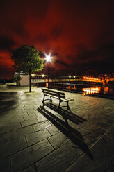 Spanien, Galicien, Naron, Promenade mit einer Bank im Vordergrund bei Nacht - RAE000468