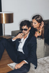 Stylish young couple with glasses of champagne at sofa - CHAF001439