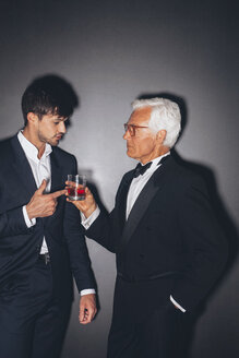 Junger Mann im Gespräch mit einem eleganten älteren Mann bei einem Getränk - CHAF001452