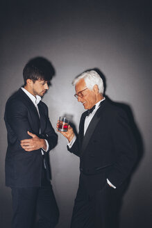 Junger Mann und eleganter älterer Mann mit einem Getränk im Gespräch - CHAF001453