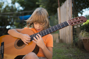 Spanien, Langhaariger blonder Junge spielt spanische Gitarre im Freien - RAEF000464