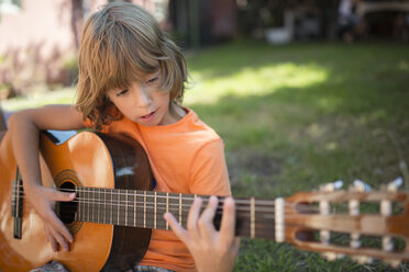 Spanien, Langhaariger blonder Junge spielt spanische Gitarre im Freien - RAEF000463