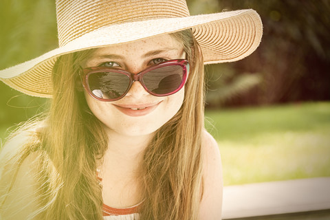 Porträt eines lächelnden Mädchens mit Sommerhut und Sonnenbrille, lizenzfreies Stockfoto