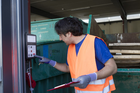 Arbeiter an einem Abfallcontainer, der eine Maschine bedient, lizenzfreies Stockfoto