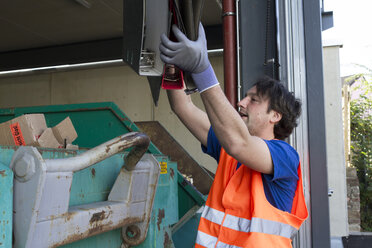 Arbeiter an einem Abfallcontainer beim Wegwerfen von Ordnern - SGF001866