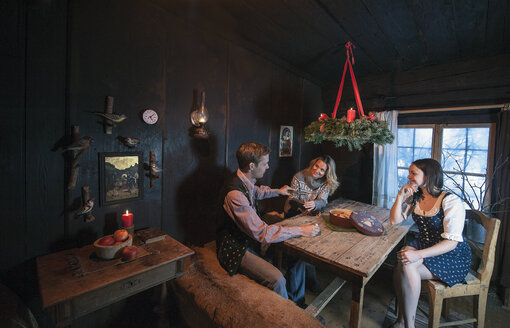 Drei Freunde verbringen gemeinsam Zeit in einem Bauernhauszimmer im Advent - HHF005407