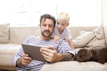 Man and his little son relaxing with digital tablet in the living room - MFRF000390