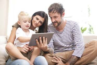 Eltern und kleiner Sohn sitzen auf der Couch mit digitalem Tablet - MFRF000456