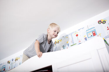 Kleiner Junge klettert auf Kleiderschrank im Kinderzimmer - MFRF000418