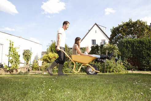 Man pushing wheelbarrow with mother and his little son through the garden - MFRF000454