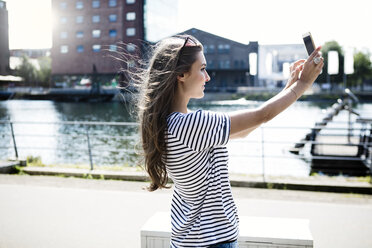 Deutschland, Duisburg, junge Frau macht ein Selfie mit Smartphone - GDF000863