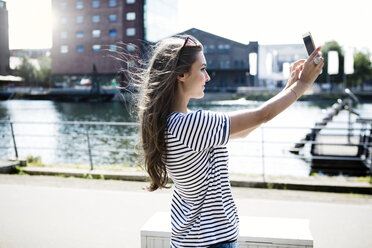 Germany, Duisburg, young woman taking a selfie with smartphone - GDF000863