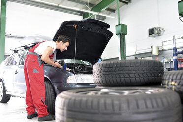 Automechaniker in einer Werkstatt, Autoreifen im Vordergrund - LYF000494