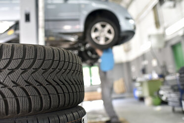 Automechaniker in einer Werkstatt, Autoreifen im Vordergrund - LYF000508