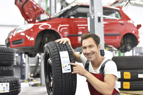 Automechaniker in einer Werkstatt beim Reifenwechsel, Energieausweis - LYF000529