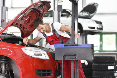 Automechaniker bei der Arbeit in einer Reparaturwerkstatt, Einstellung von Autoscheinwerfern - LYF000516