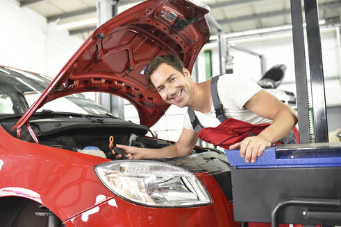 Automechaniker bei der Arbeit in einer Reparaturwerkstatt, Einstellung von Autoscheinwerfern - LYF000518