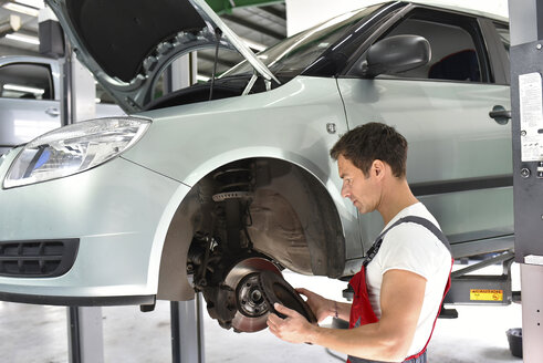 Automechaniker bei der Arbeit in einer Reparaturwerkstatt, Überprüfung der Bremsscheiben - LYF000525