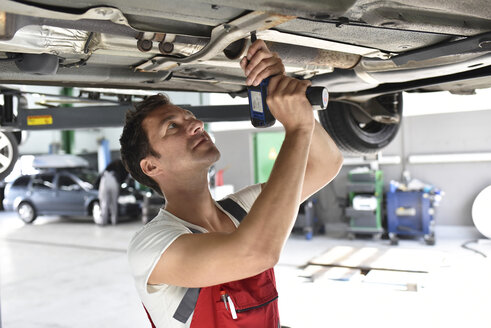 Automechaniker bei der Arbeit in einer Reparaturwerkstatt, Reparatur des Unterbodens - LYF000527