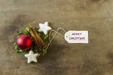 Weihnachtsdekoration mit Zimtstangen und Sternen und einer roten Christbaumkugel auf Holz - ODF001307