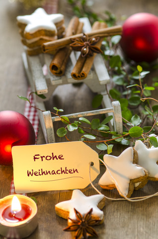 Weihnachtsdekoration mit Miniaturschlitten, Teelicht und Zimtsternen, lizenzfreies Stockfoto