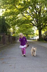 Porträt eines lachenden kleinen Mädchens, das mit seinem Hund spazieren geht - JFEF000697