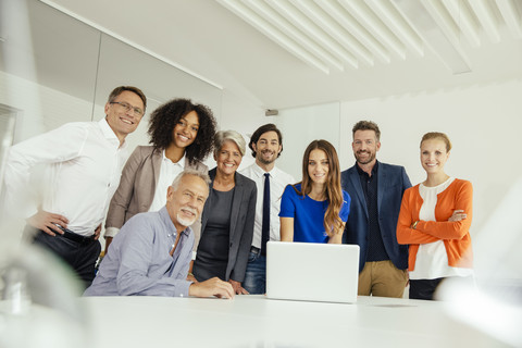 Portrait of smiling business people with laptop in conference room stock photo