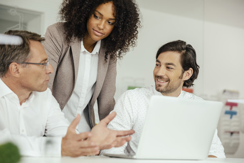 Drei Geschäftsleute besprechen sich in einem Konferenzraum, lizenzfreies Stockfoto