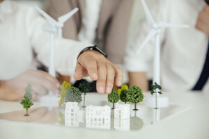 Close-up of business people wind turbine model and houses on conference table - MFF002154