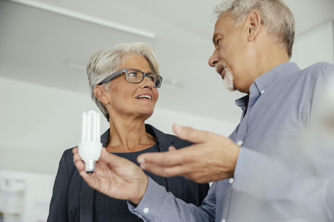 Businesswoman and businessman talking about energy-saving lightbulb stock photo