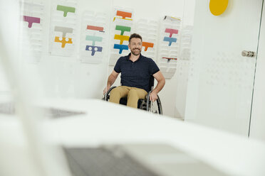 Lächelnder Mann im Rollstuhl in einem modernen Büro - MFF002209