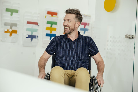 Smiling man in wheelchair in modern office stock photo