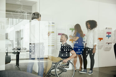 Colleagues talking in office with one sitting in wheelchair - MFF002175