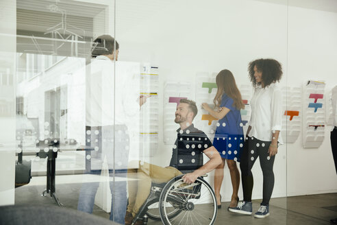 Kollegen unterhalten sich im Büro, einer sitzt im Rollstuhl - MFF002175